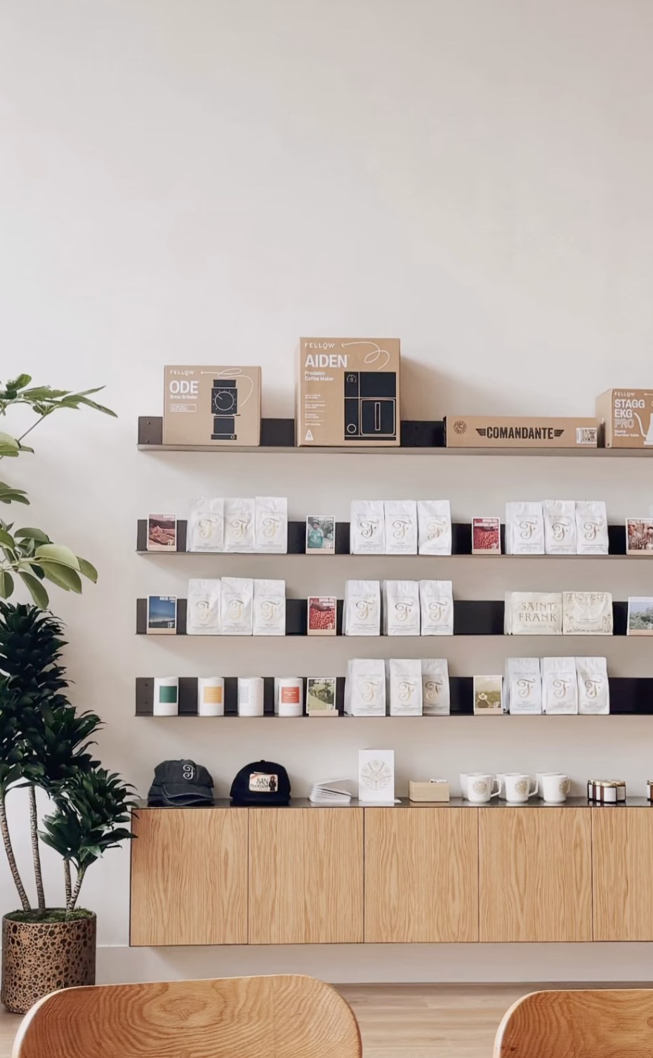 The retail wall of brewing gear and branded coffee bags at Saint Frank Coffee